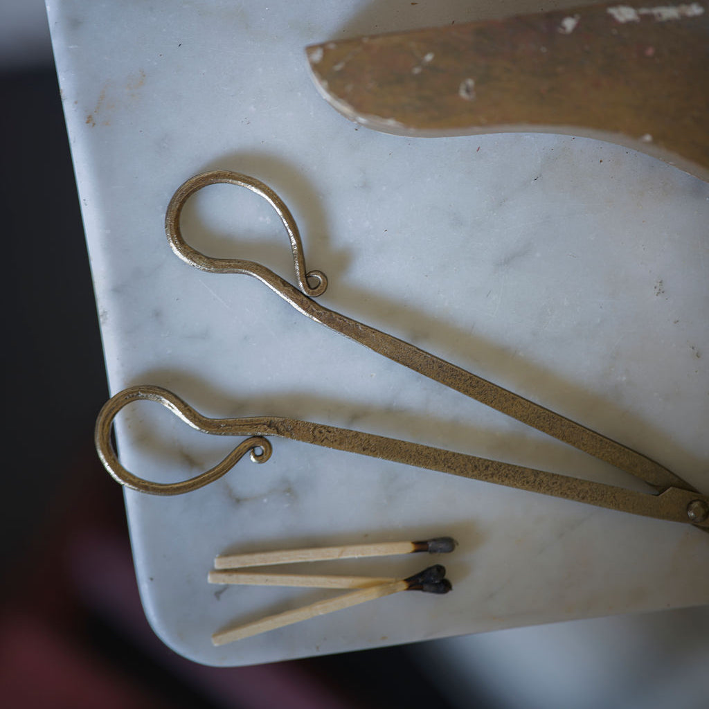 Brass wick trimmers and matches on a marble surface
