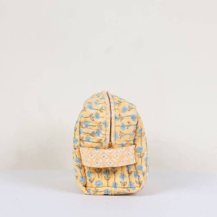 Yellow floral-patterned washbag on a light beige background