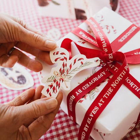 Gift box with red ribbon and decorative tag on a checkered tablecloth