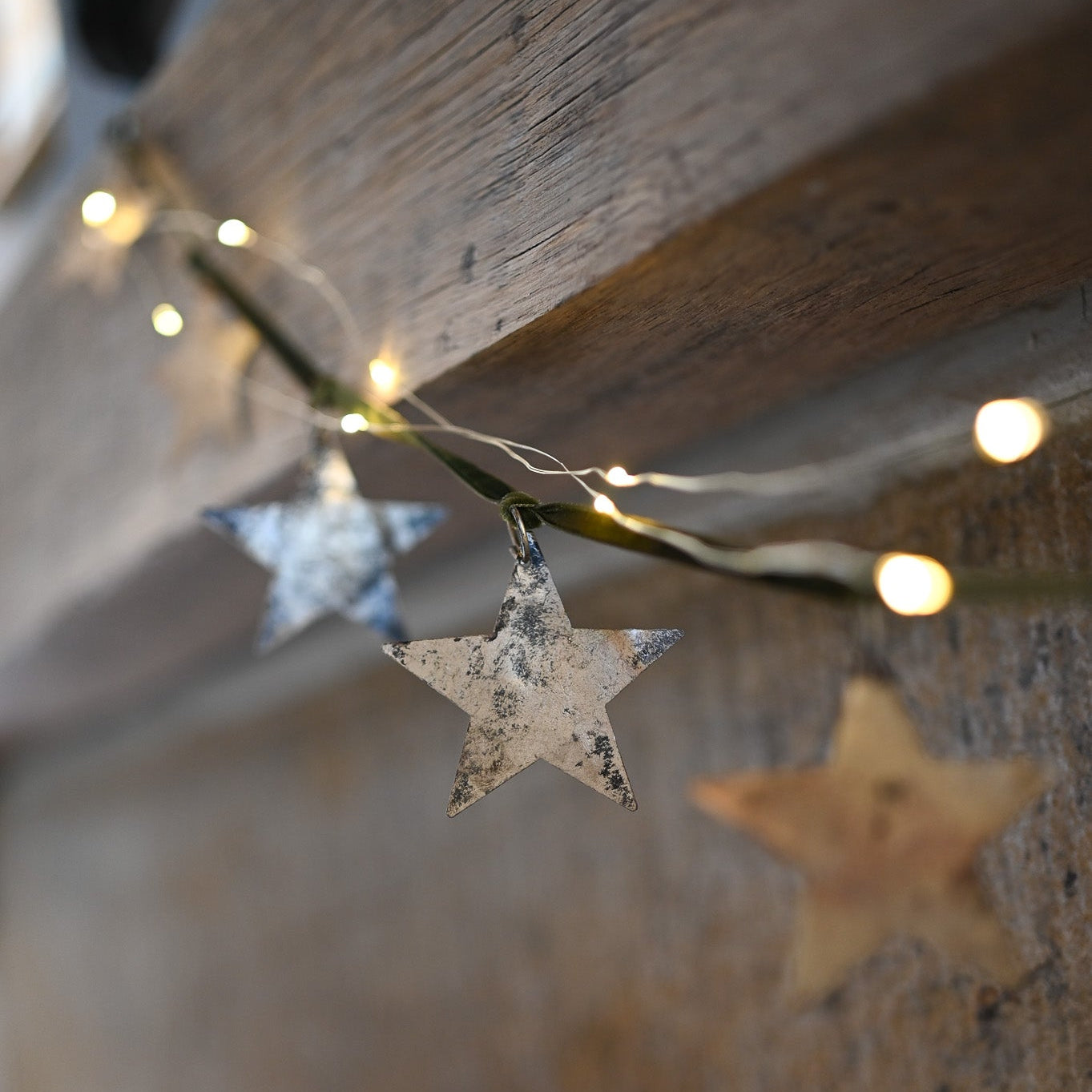 Star-shaped Garland hanging on a wooden surface with string lights.