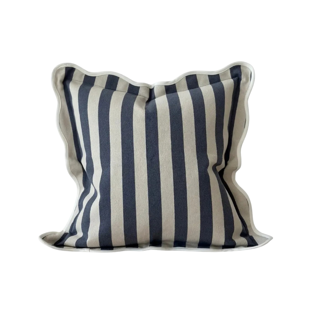 A square cushion with vertical navy blue and cream stripes, finished with a cream scalloped edge trim.