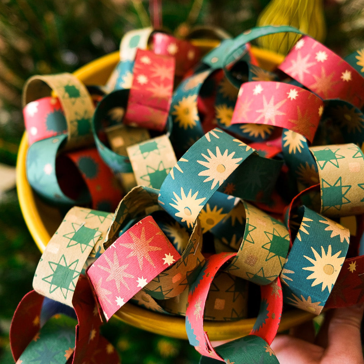 Colourful paper chains held by a hand against a blurred natural background