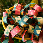 Load image into Gallery viewer, Colourful paper chains held by a hand against a blurred natural background
