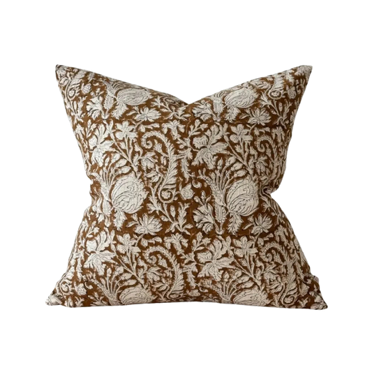 A square decorative cushion featuring an intricate floral and botanical damask pattern in brown and cream, set against a plain cream background.