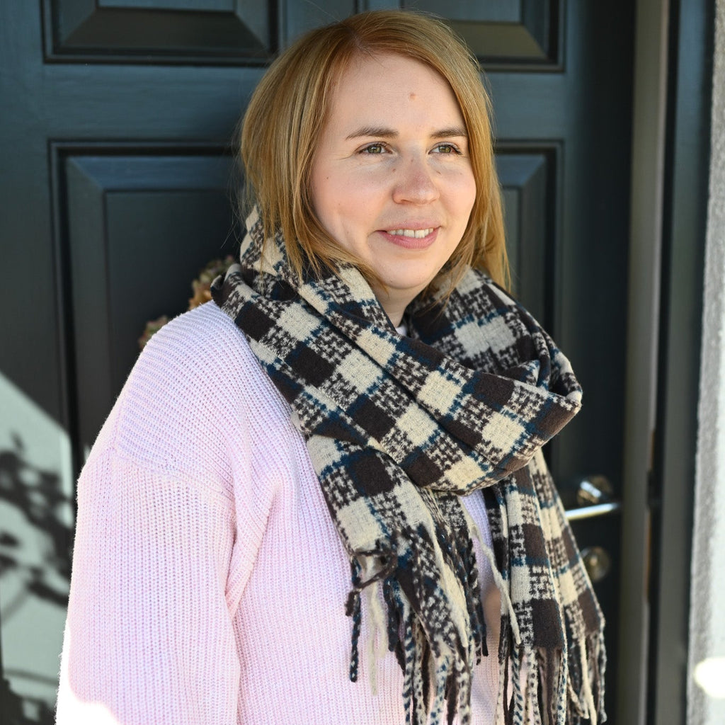 Woman wearing a check scarf in front of a dark door