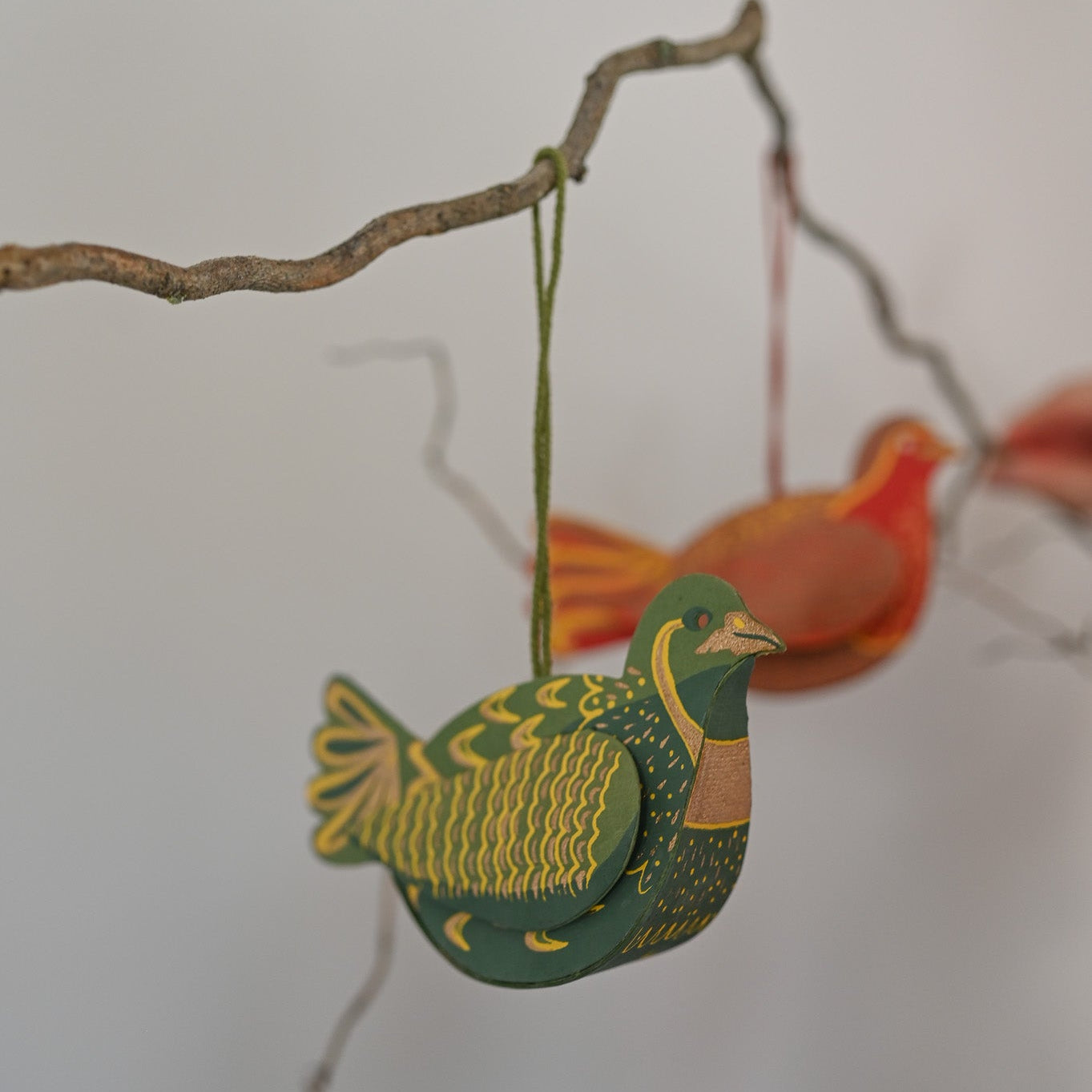 Decorative bird decoration hanging on a branch against a white background