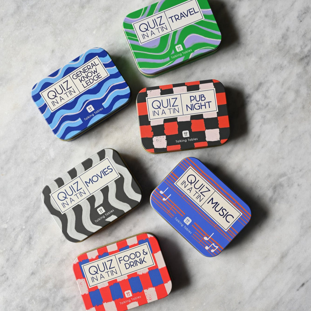 Set of colourful quiz-themed tins on a marble surface