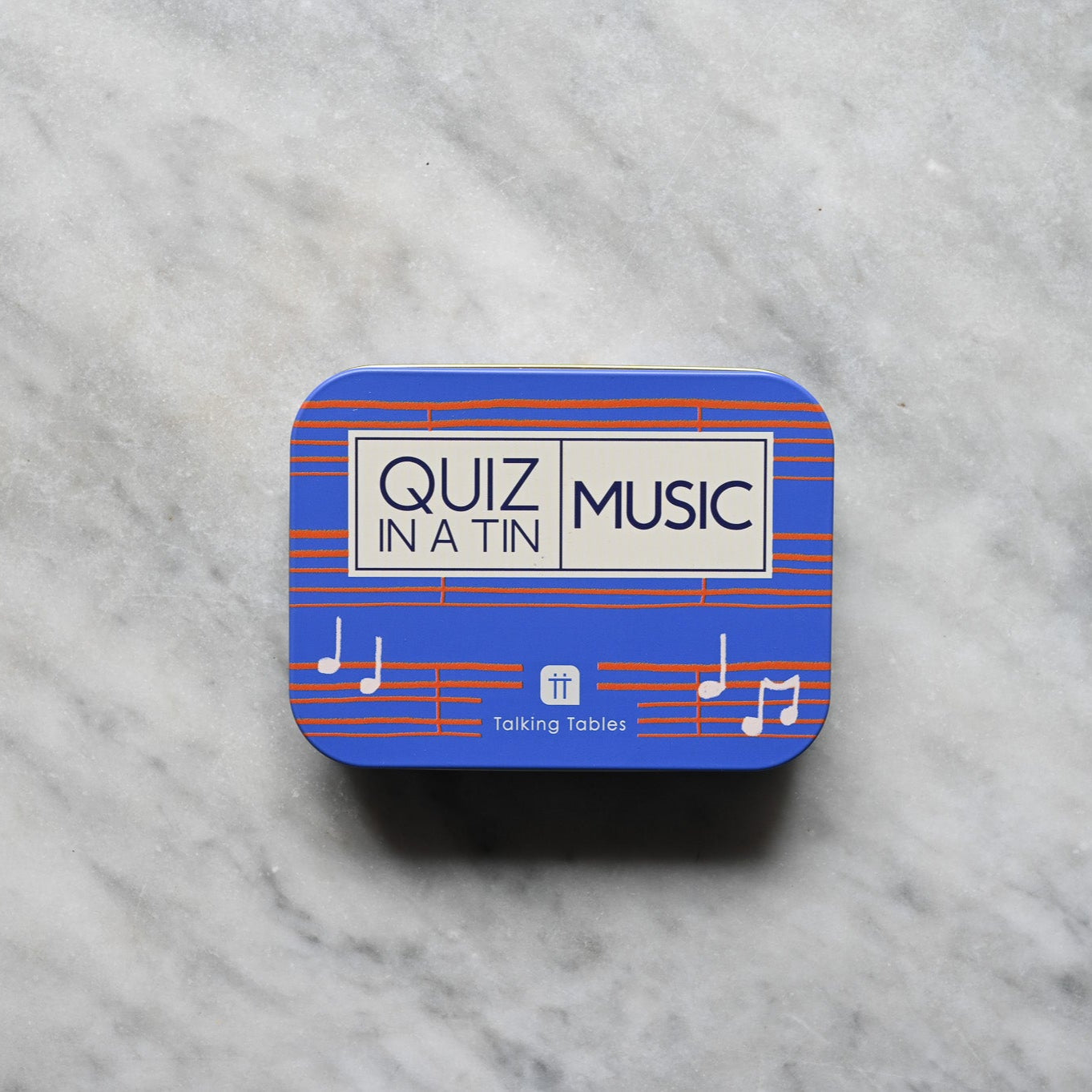 Blue tin with 'Quiz in a Tin Music' text on a marble surface