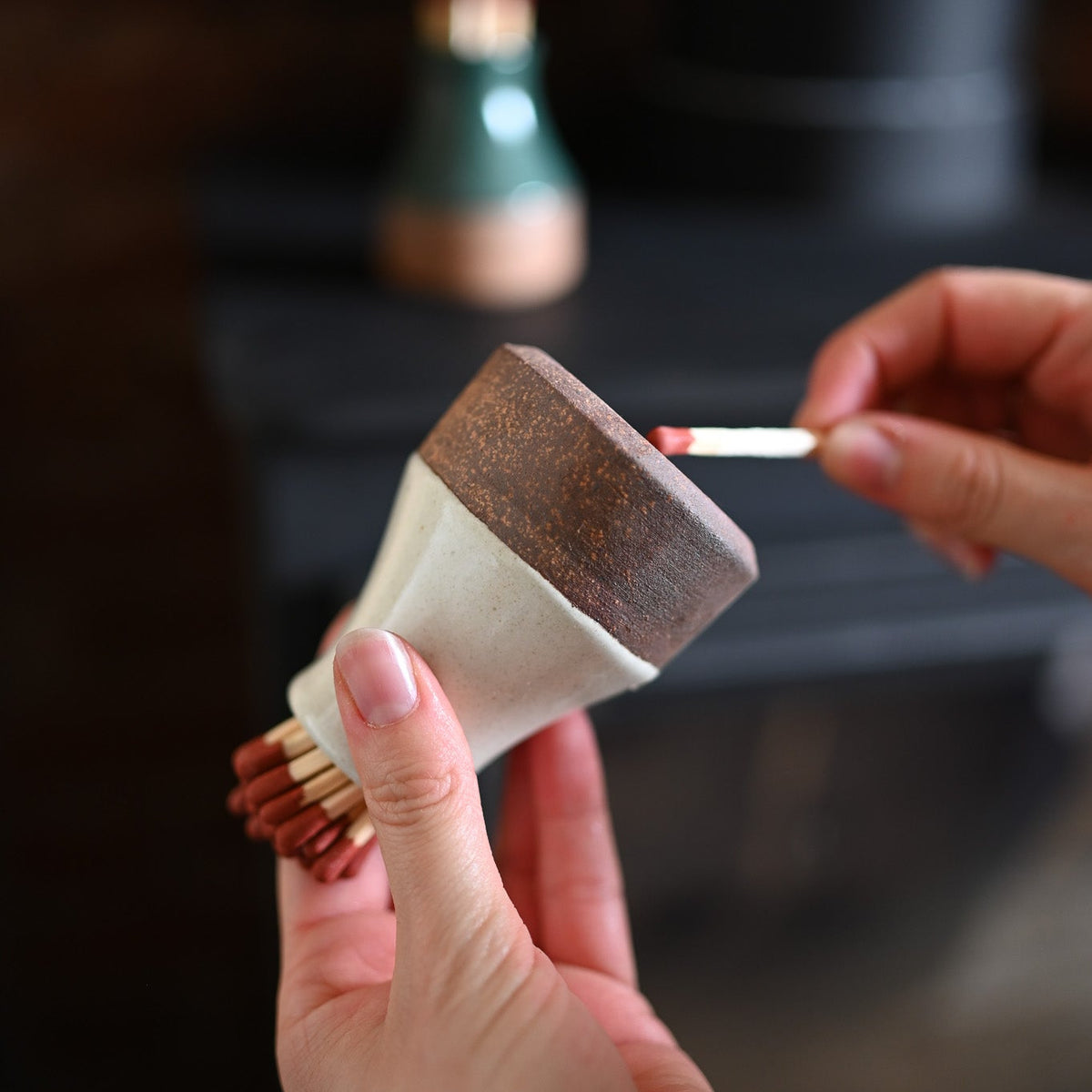 Person lighting a match with a small milk bottle
