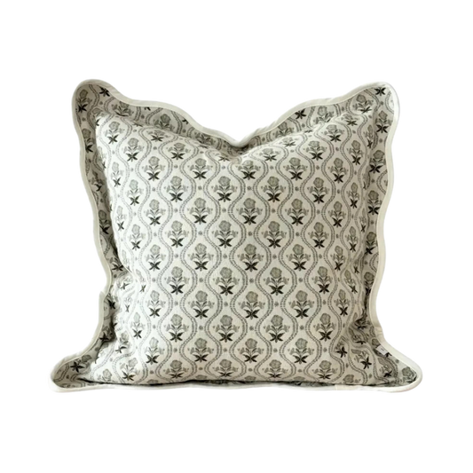 A square decorative cushion with a green and off-white floral trellis pattern and a scalloped edge, shown on a off white background.