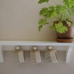 Load image into Gallery viewer, Potted plant on a white shelf with hooks and ridged mugs hanging.
