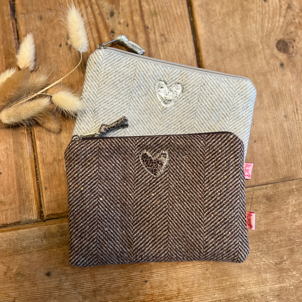 Two zipped purses with heart designs on a wooden surface