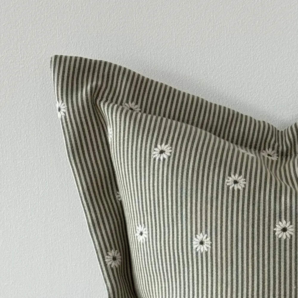 Striped cushion with floral patterns on a light gray background