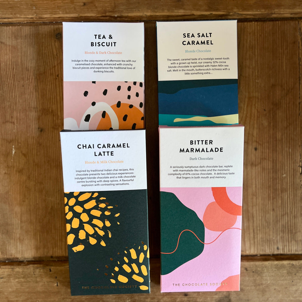 Four Chocolate bars with colorful designs and text on a wooden surface