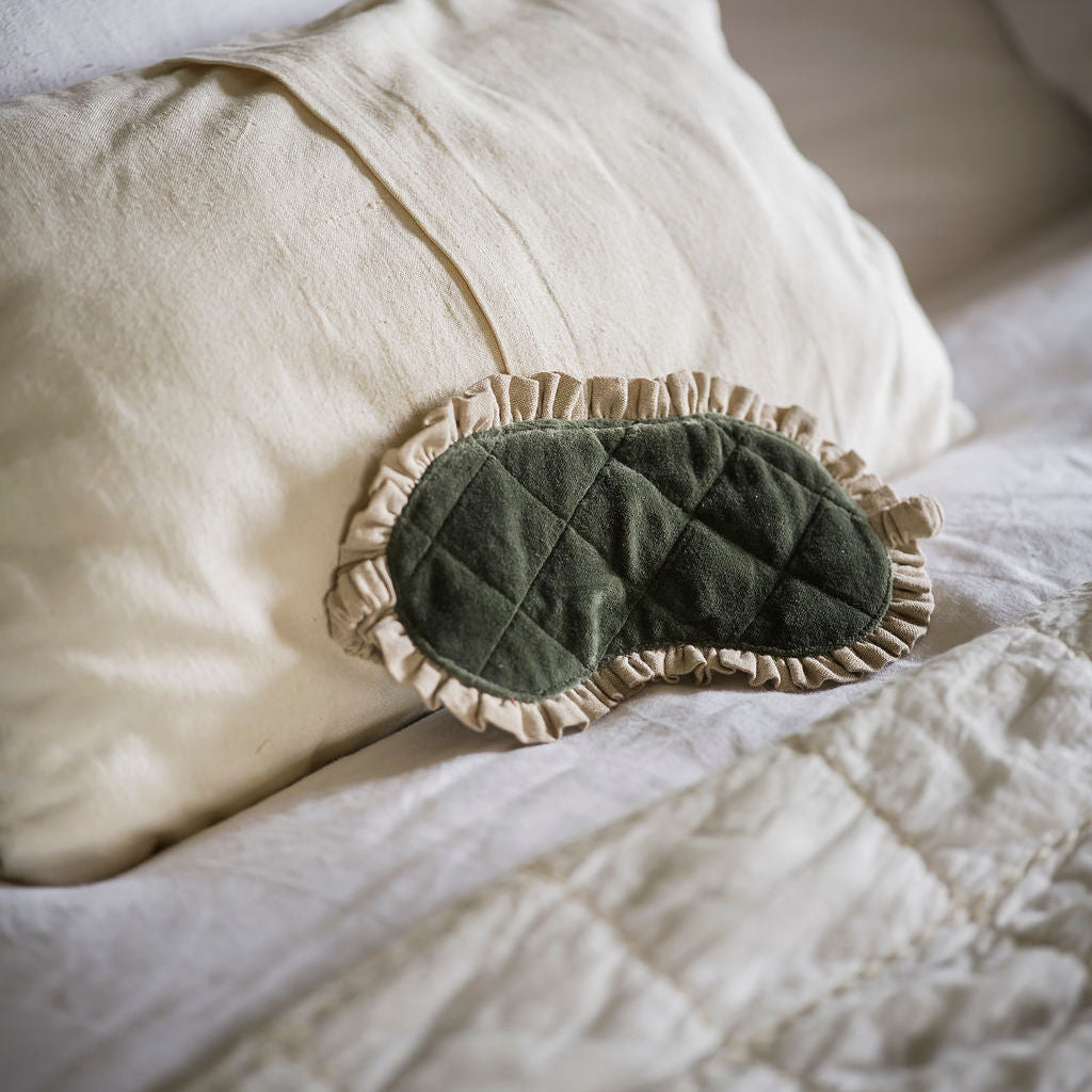 Green quilted eye mask on a white pillow