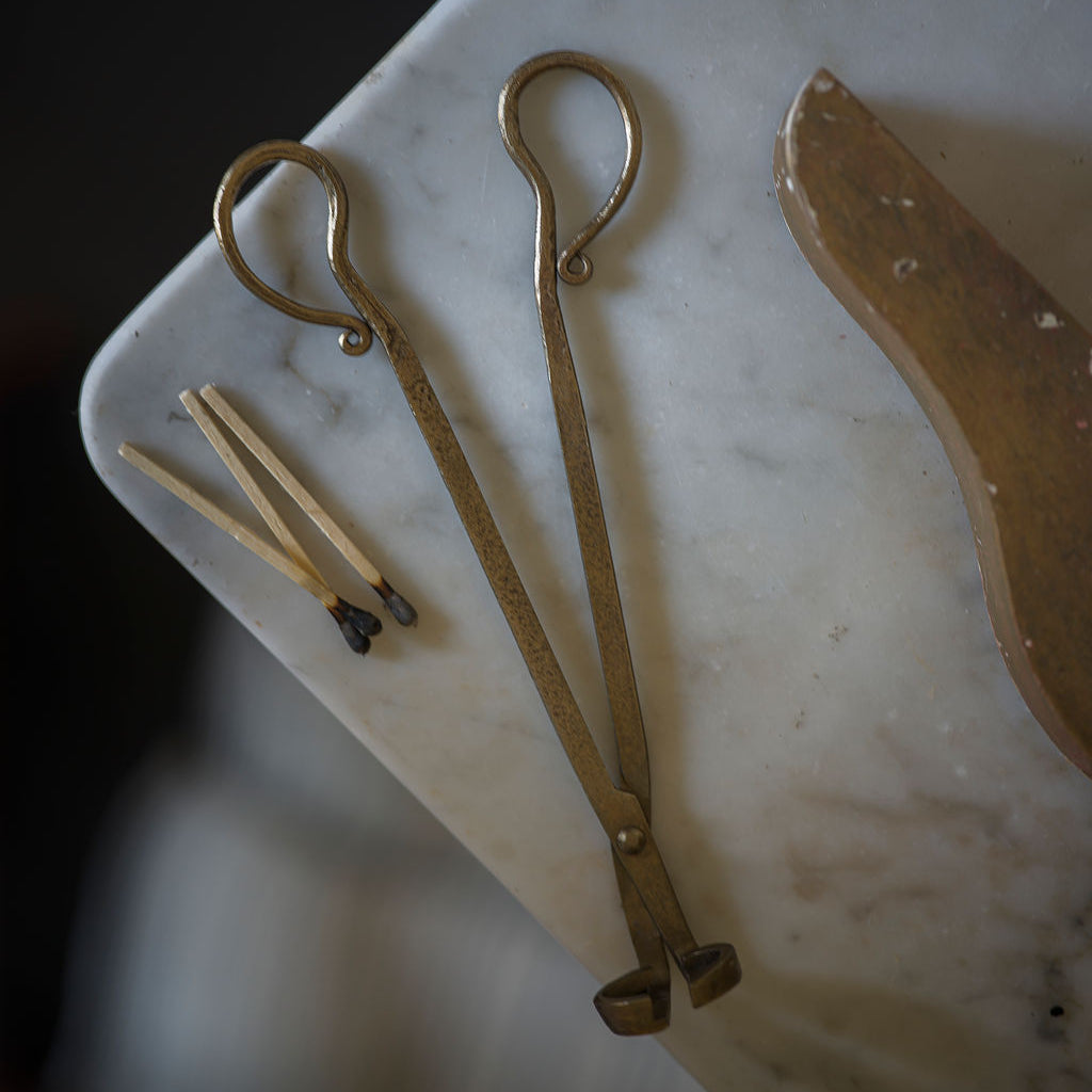 Two brass tongs on a marble surface