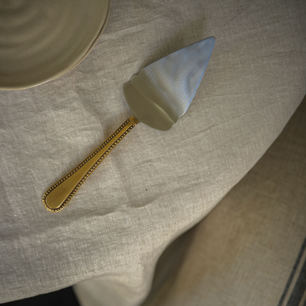 Cake slice with a gold, antique style handle on a textured surface