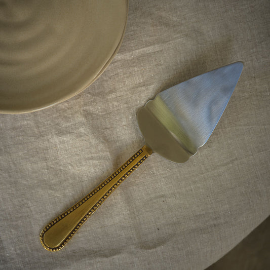 Cake slice with a gold, antique handle on a textured surface