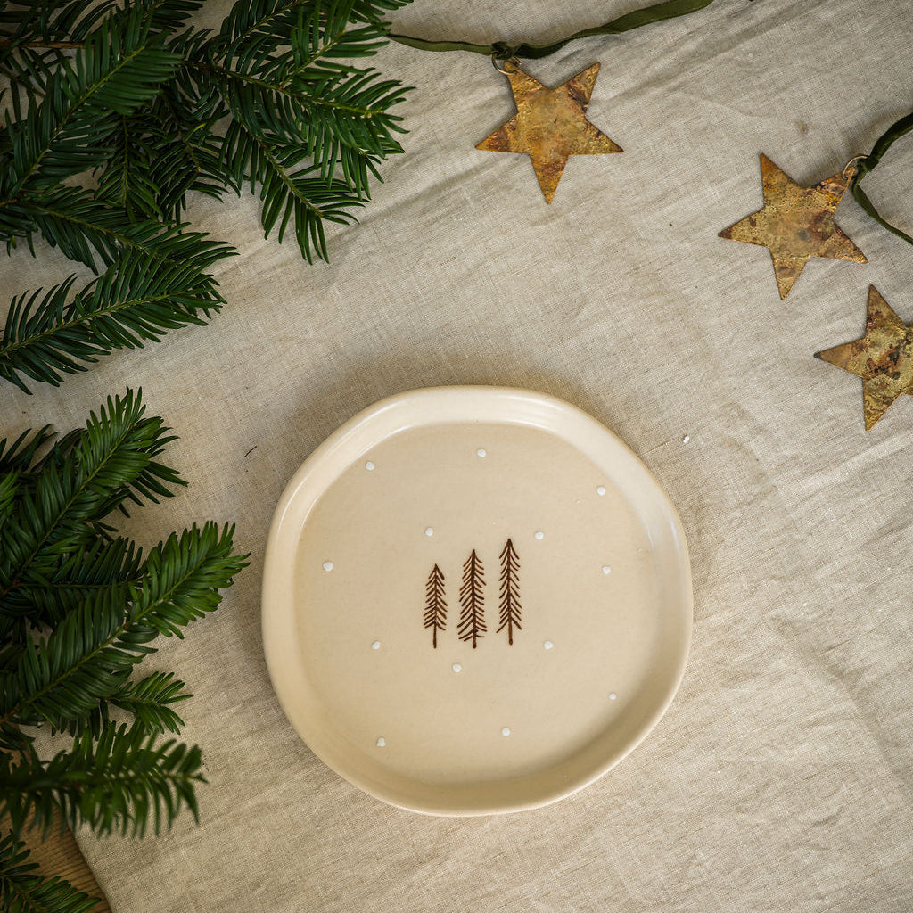 Decorative plate with tree design on a textured surface with greenery and stars.