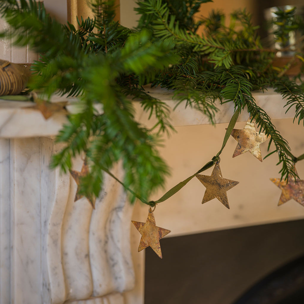Decorative Christmas garland with star-shaped ornaments on a fireplace mantel.