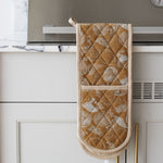 Load image into Gallery viewer, Quilted mustard oven mitt hanging on a kitchen cabinet with marble backsplash
