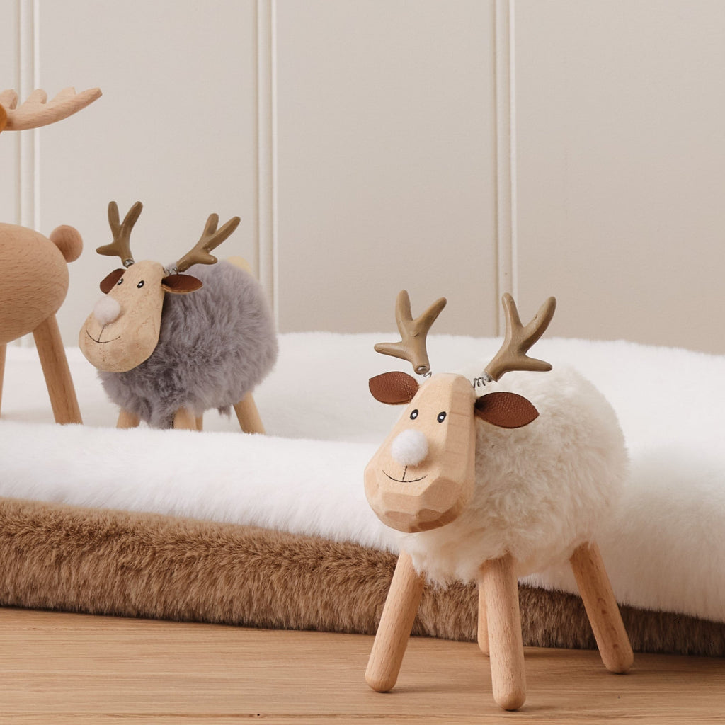 Two wooden deer figurines on a white surface with a neutral background