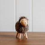 Load image into Gallery viewer, Small wooden sheep figurine on a wooden surface with a white paneled wall background
