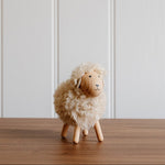 Load image into Gallery viewer, Small sheep figurine on a wooden surface with a white paneled wall background
